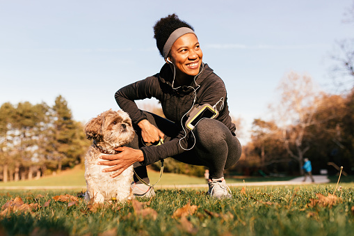 Happy African American athlete enjoying with her dog in the park.