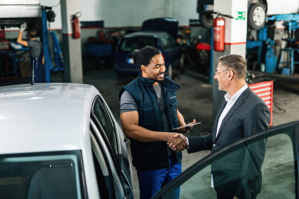 Don't worry, I'll repair your car! Happy African American car mechanic shaking hands with a customer in auto repair shop. auto repair shop mechanic digital tablet customer stock pictures, royalty-free photos & images