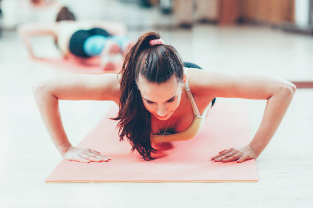 l'athlète féminine active de mode de vie pousse vers le haut le tapis de yoga - athlete push ups muscular build female photos et images de collection