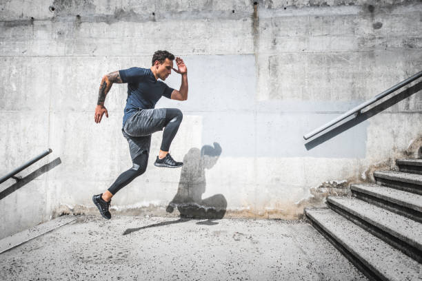 Experienced Male Athlete Running Stairs with High Knees Flexible young male athlete showing flexibility and endurance as he starts the last of a three-tiered staircase workout. hard and fast stock pictures, royalty-free photos & images