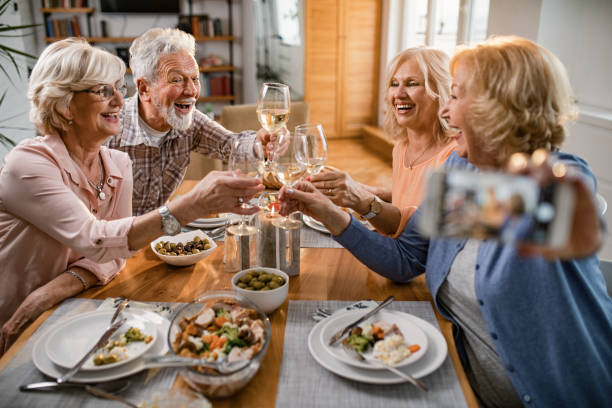 istock Group of happy seniors toasting with wine while taking selfie at dining table. 1191771999