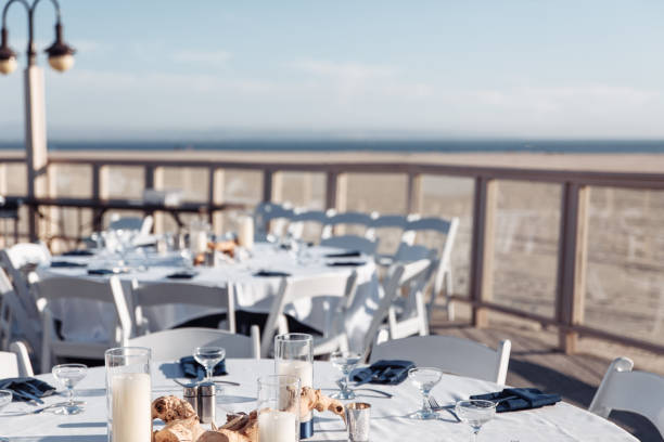 istock Round table with white tablecloths, navy blue napkins, wooden rustic natural deroations and candles on the wooden deck on the beach 1191773099