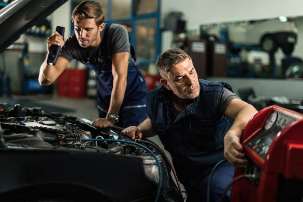 istock Auto mechanics cooperating while repairing car's air conditioning system in a garage. 1191773757