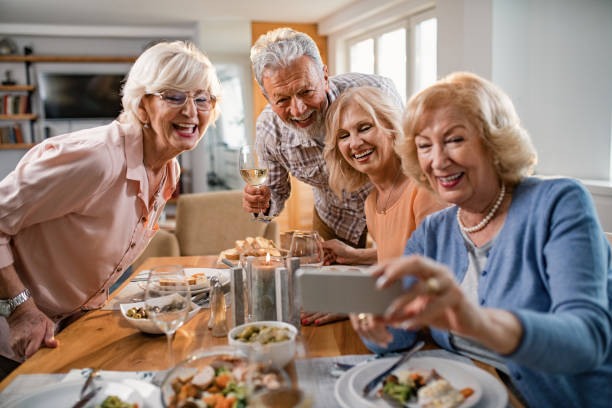 istock Group of cheerful mature friends having fun while taking selfie at dining table. 1191774188