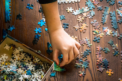 Overhead view - A child's had working on a puzzle, jigsaw, putting it together.