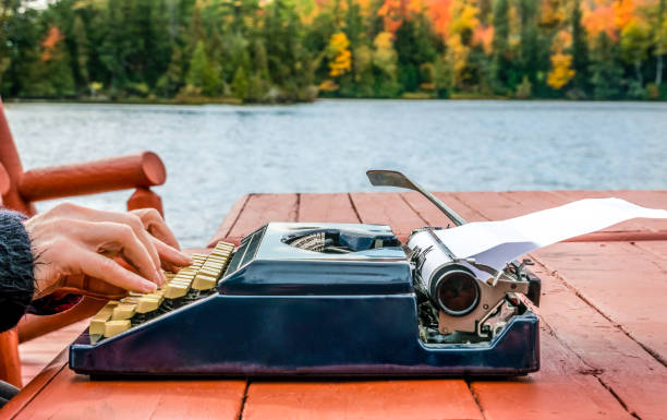 istock Work from anywhere - working on typewriter beneath the autumn sky while on a deck near the water's edge. concept - background 1191774726