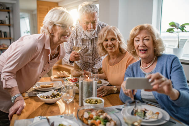 istock Happy seniors friends having fun while taking selfie during lunch at home. 1191775186