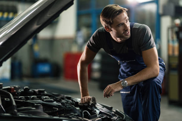 istock Young mechanic working on car engine in auto repair shop. 1191777850