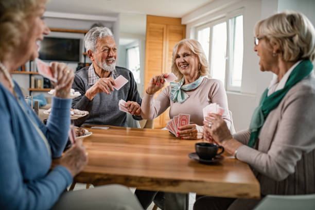istock Happy seniors talking while playing cards at home. 1191779966