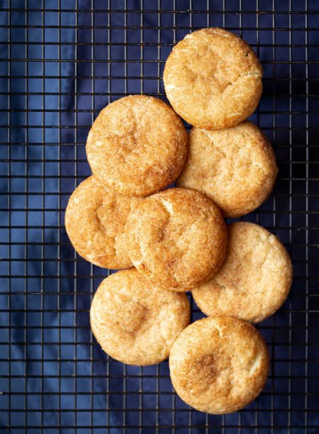 Traditional snickerdoodle cookies Overhead view of freshly baked snickderdoodle cookies on a cooling rack with a dark blue linen underneath round sugar cookie stock pictures, royalty-free photos & images