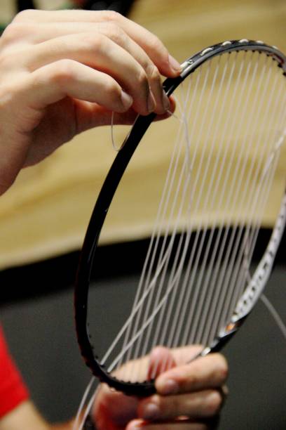 mains de l'homme fixe une raquette de badminton. pas de gens. régule la tension de la chaîne de la raquette de badminton, verticale - racket string photos et images de collection