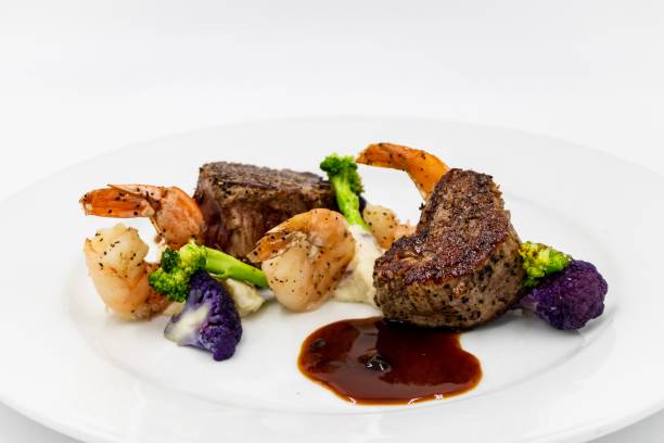 Surf and Turf Filet Mignon with Shrimp and mixed vegetables with a red wine reduction on a white background dre stock pictures, royalty-free photos & images