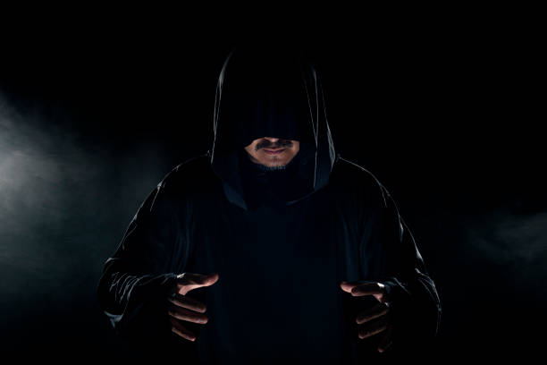 Cult Leader Wearing a Dark Robe with Smoky Background Man dressed in a dark robe looking like a cult leader on a smoky or foggy background.  He looks like a creepy evil villain ceremonial robe stock pictures, royalty-free photos & images