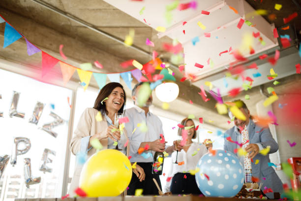 Celebrating birthday with confetti Coworkers celebrating birthday in office. anniversary stock pictures, royalty-free photos & images