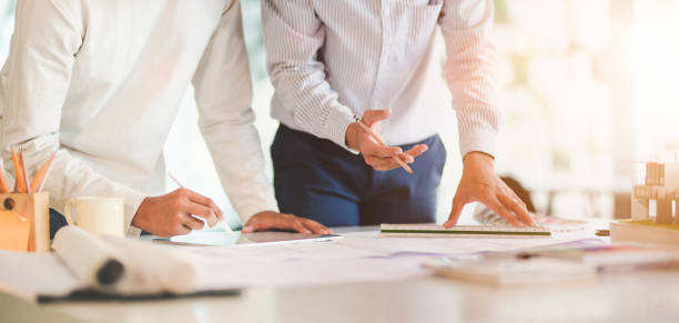 istock Close-up view of young professional architect and engineer working together on construction plans in modern office 1191790607