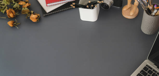 istock Top view of modern workplace with laptop computer and office supplies on dark grey table 1191790622