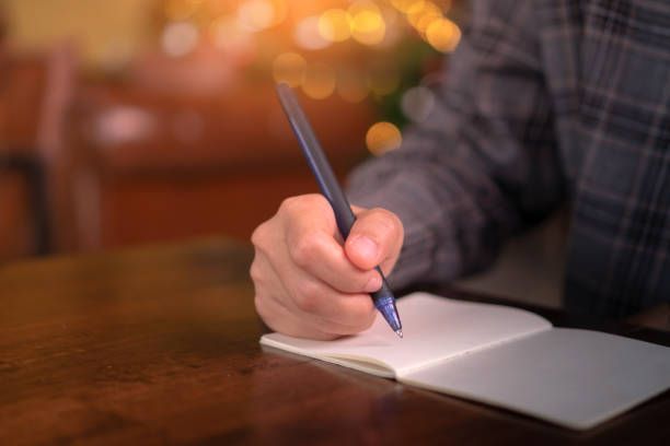 istock Woman hand writing down in small white memo notebook for take a note not to forget or to do list plan for future. 1191798472