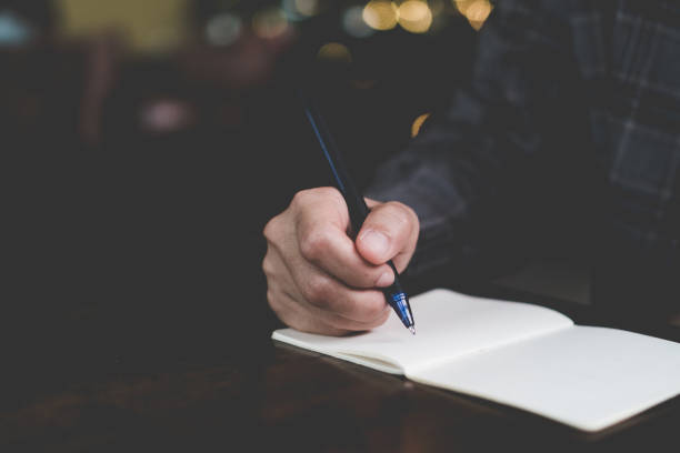istock Woman hand writing down in small white memo notebook for take a note not to forget or to do list plan for future. 1191798994