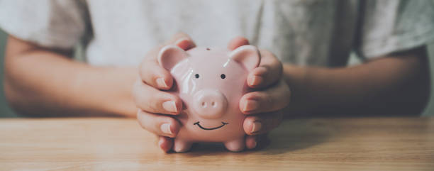 imagen panorámica, hombre mano sosteniendo alcancía en la mesa de madera. ahorre dinero e inversión financiera - pension retirement planning savings fotografías e imágenes de stock