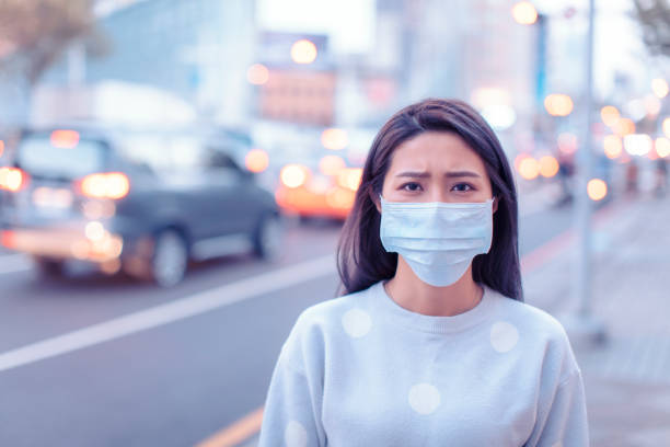 young  woman wear mask in the city during smog day - illness mask pollution car imagens e fotografias de stock