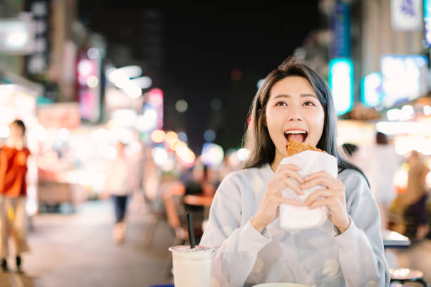 アジアの女性は夜市でストリートフードでチキンフィレを楽しむ - food chinese ethnicity street china ストックフォトと画像