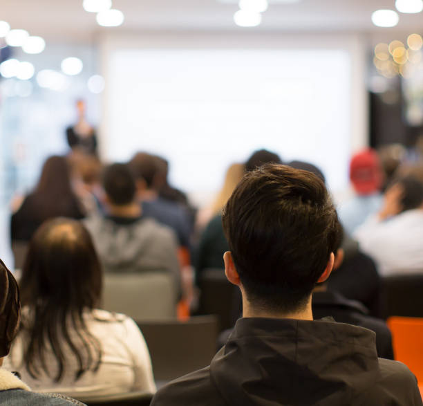 istock Conference photo audience and speaker giving speech. Seminar presenter on a panel during forum. Corporate manager in sales executive training discussion on stage. Investor pitch presentation. 1191811487