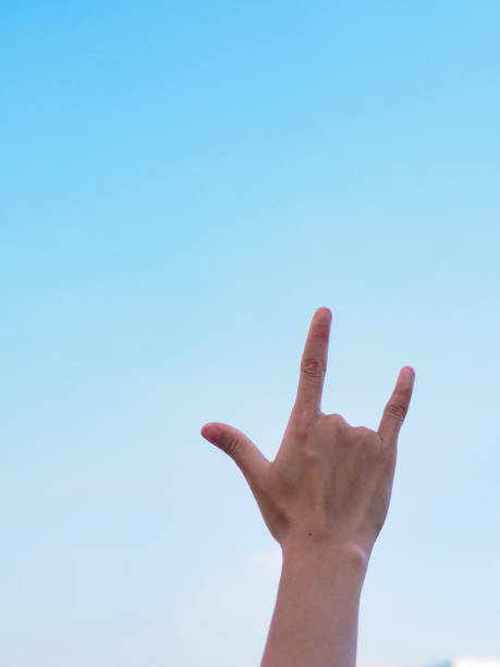istock Human hand show love sign on blue sky as a background . 1191811510