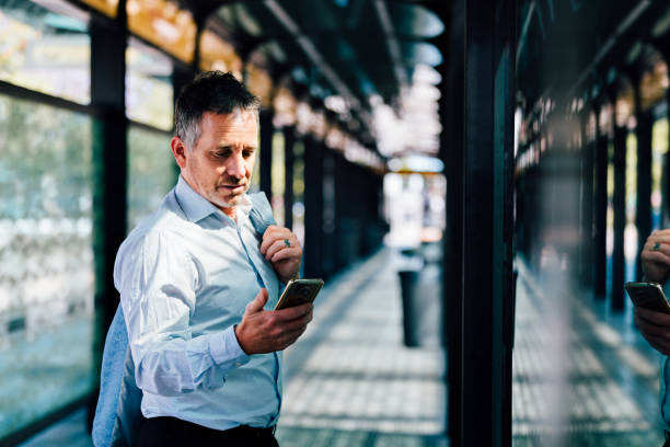 istock Businessman using mobile phone at bus stop 1191813151