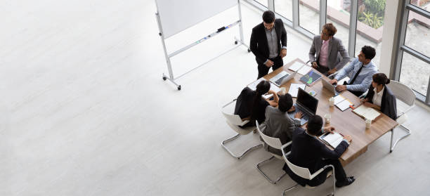 top view of group of multiethnic busy people working in an office, aerial view with businessman and businesswoman sitting around a conference table with blank copy space, business meeting concept - board room business meeting office imagens e fotografias de stock
