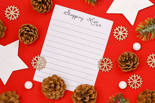 istock Concept for Christmas shopping with top view flat lay with empty shopping check list and seasonal decorations like pine cones and stars on bright red background 1191818340