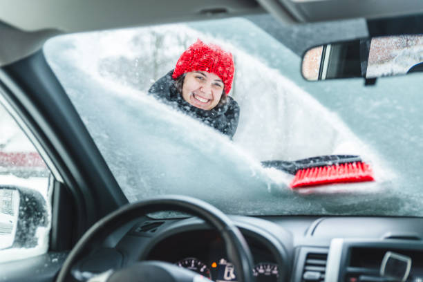 young pretty woman cleaning car after snow storm - winter driving imagens e fotografias de stock