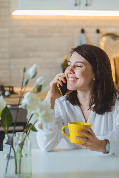 istock woman drinking tea from yellow mug at the kitchen 1191820551
