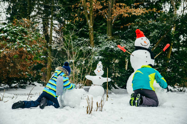 istock little cute boy making snowman. rolling big snowball 1191820560