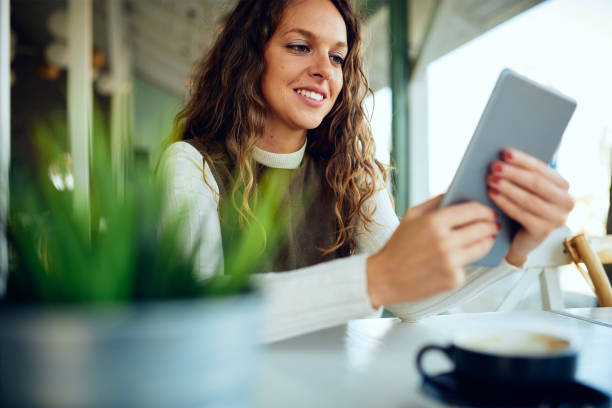 istock Attractive young curly brunette looking at her tablet and smiling 1191821077