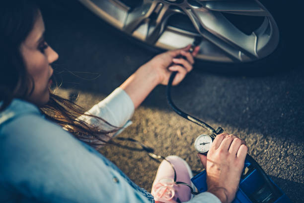 Measuring pressure in a car tire. Close up of a woman using compressor to inflate car tire. inflating stock pictures, royalty-free photos & images
