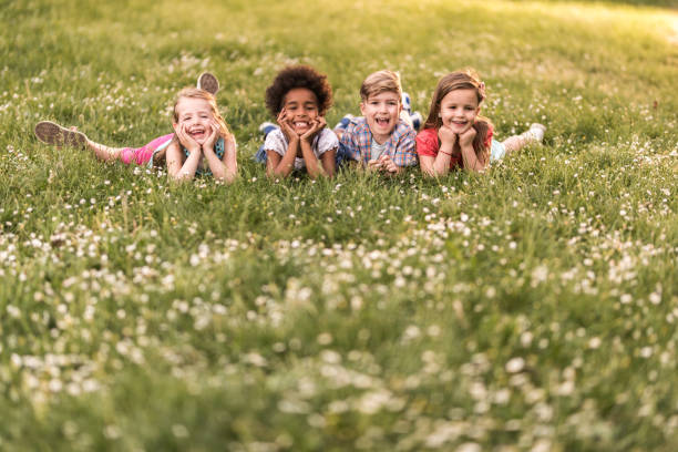 istock Happy children enjoying in spring day while lying in grass and looking away. 1191822513