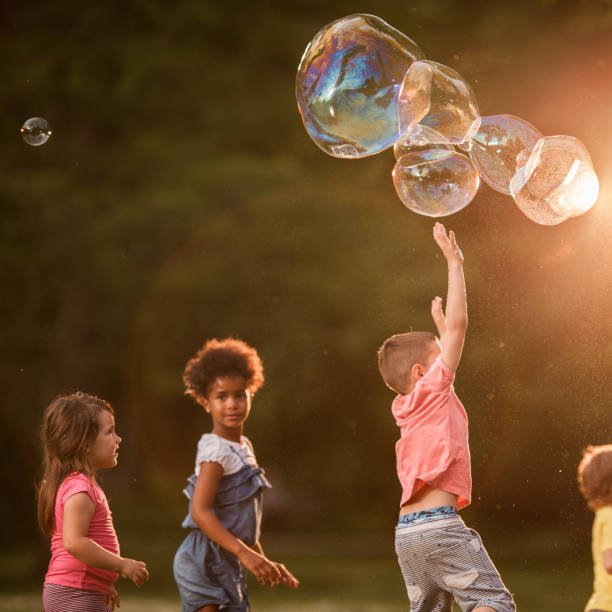 istock Carefree kids having fun while catching bubbles in nature. 1191822961