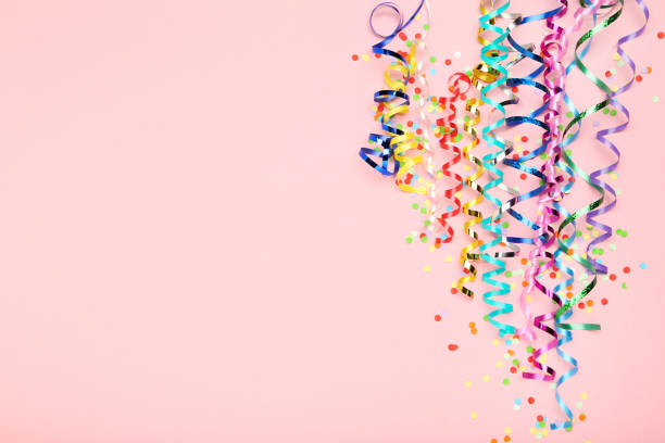 istock Colorful ribbons with confetti on pink background 1191825318