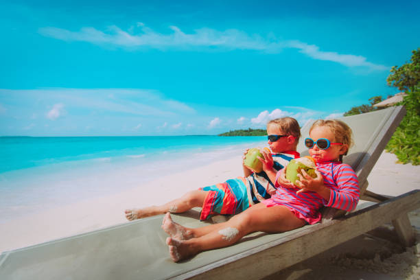 istock little boy and girl drinking coconut on beach 1191829080
