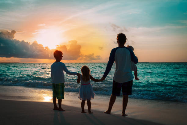 istock father and kids walking on beach at sunset 1191829176