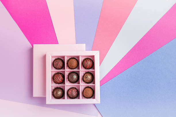 초콜릿 사탕은 컬러 종이 배경에 분홍색 상자를 설정합니다. 평면 상단 보기입니다. 공간을 복사합니다. 휴일 개념입니다. 정사각형 프레임 - chocolate candy gift package chocolate 뉴스 사진 이미지