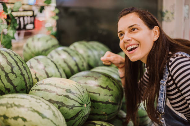 Beautiful young woman buying fresh vegetables in the market