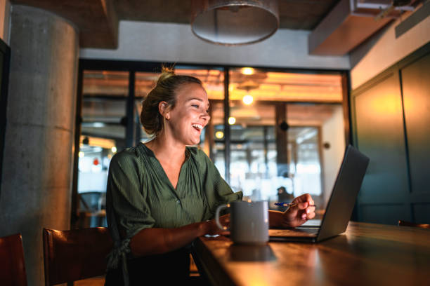 śmiejąc się młody bizneswoman wideokonferencje na laptopie - coffee board room office meeting zdjęcia i obrazy z banku zdjęć