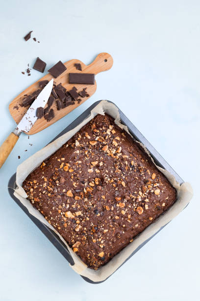 istock Chocolate brownie with nuts on square pancake mold pan, light blue background top view flat lay looking down with text space. 1191836645