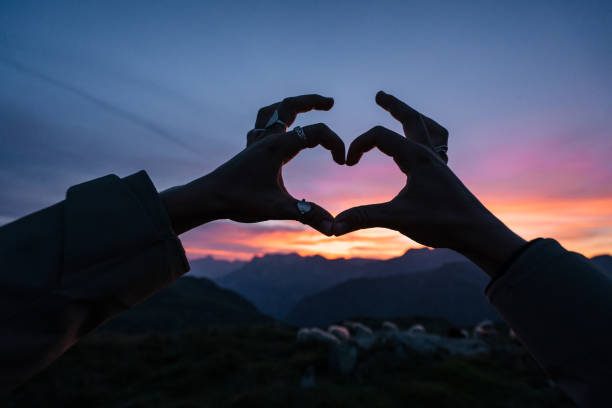 istock Young woman makes heart formation with hands at sunrise 1191837251