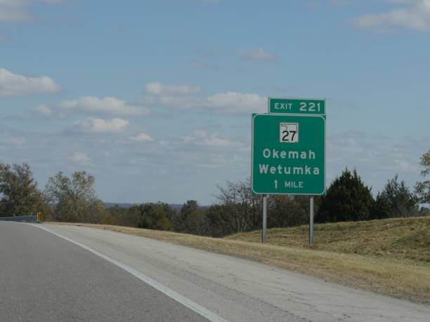 mittelweite aufnahme eines straßenschildes mit wegbeschreibungen nach okemah und wetumka in oklahoma. - oklahoma sign road sign sky stock-fotos und bilder