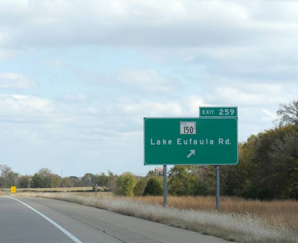 weitschuss eines schildes entlang der straße mit wegbeschreibung zum see eufala, oklahoma. - oklahoma sign road sign sky stock-fotos und bilder