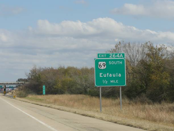 weitschuss eines straßenschildes mit abstand zu eufala, oklahoma. - oklahoma sign road sign sky stock-fotos und bilder