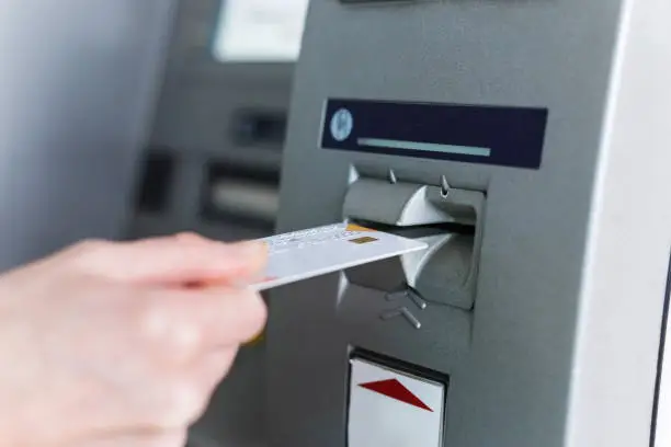 Photo of Person insert card to automated teller machine. Cashing non-cash money by individual.