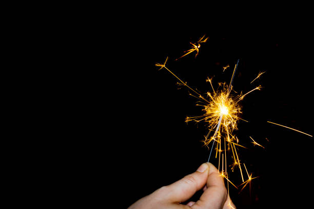 Hand holding a sparking match stick. Black background